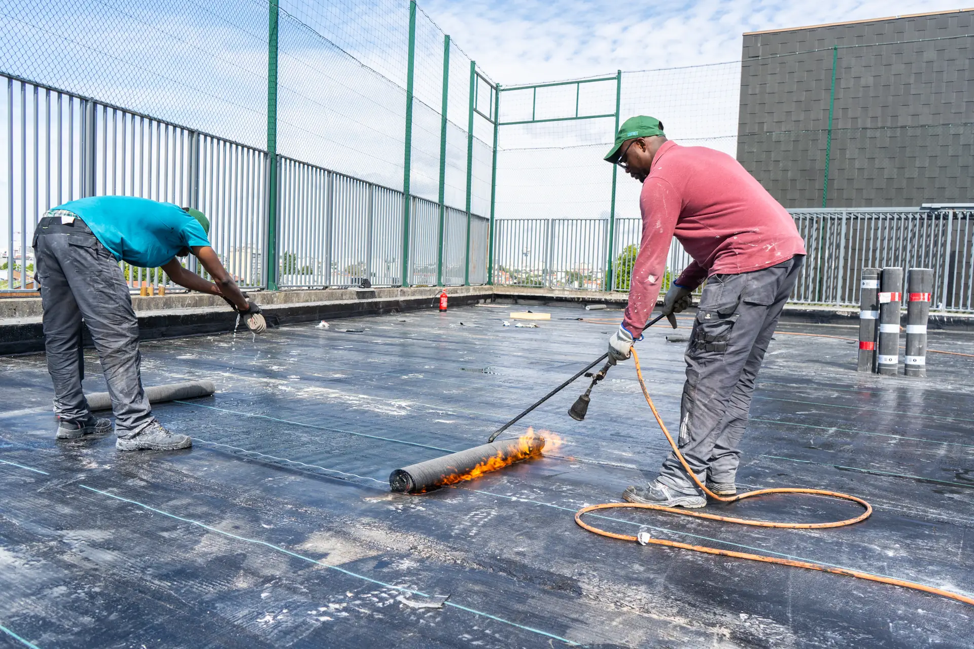 Compagnons SOFRET posant une étanchéité bitumineuse au chalumeau sur une toiture-terrasse